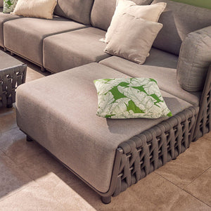Outdoor furniture set from Lawson Collection featuring a charcoal wicker lounge chair, rope chair, and rope ottoman with matching cushion, next to a light grey sofa in a cozy backyard setting.