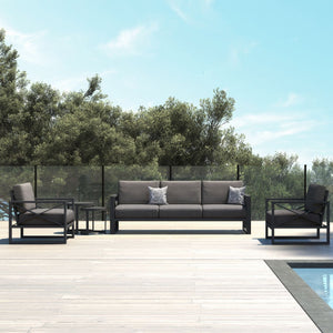 Aluminium outdoor furniture set from Linear Lounge collection, featuring a 5-seater lounge with charcoal frame and cushions, located outdoors with trees in the background.